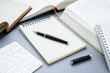 © patpitchaya - Closeup a pen on the empty notebook with many books around on the table, create a new content, research, and collect the information