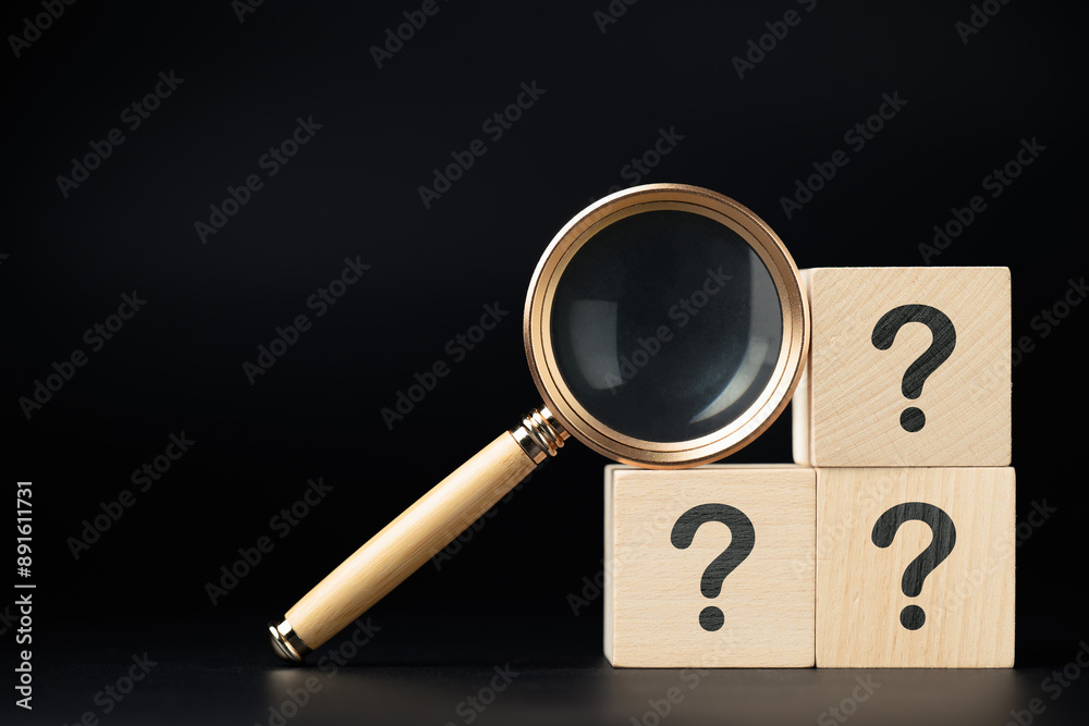 Magnifying glass and stack of question mark wood cubes, analyze the ...