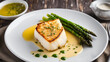 © arayabandit - Pan-seared Chilean sea bass served with a rich beurre blanc sauce and fresh asparagus spears, adding a touch of freshness to this elegant dish.