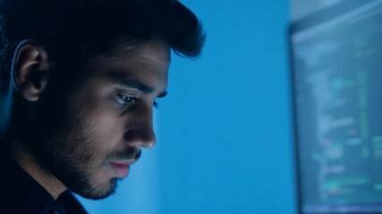 Poster - A man is staring at a computer screen with a blue background. He is focused on the screen and he is working on a project