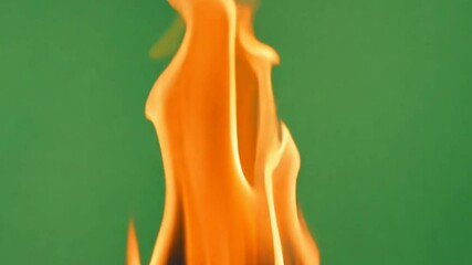 Fototapete - A close up of a flame on a green background. The flame is yellow and orange, and it is dancing in the air. Concept of warmth and energy, as well as a feeling of movement and life