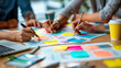 © weerasak - Team collaboration with colorful sticky notes and brainstorming session on wooden table, focusing on creativity and planning.