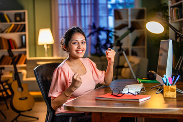 Wall Mural - Indian asian  young student or businesswoman using laptop with coffee, books, smartphone, headphone