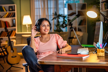 Wall Mural - Indian asian  young student or businesswoman using laptop with coffee, books, smartphone, headphone