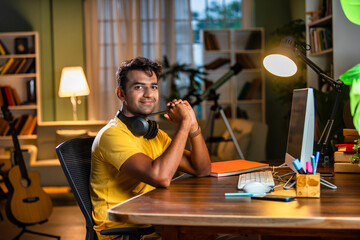 Wall Mural - Indian asian  young student or businessman using laptop with coffee, books, smartphone, headphone.