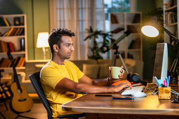 Wall Mural - Indian asian  young student or businessman using laptop with coffee, books, smartphone, headphone.