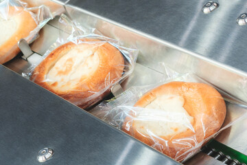 Poster - Three pieces of bread are in plastic bags and are being processed by a machine. The bread is white and he is a type of pastry