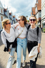 three cheerful young adult women friend walk street old european german town city street enjoy havin