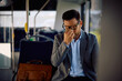 © Drazen - Exhausted businessman having  headache while commuting by bus.