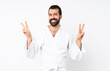 © luismolinero - Young man doing karate over isolated white background showing victory sign with both hands
