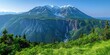 © Ross - Majestic snow-capped mountain range with lush green valley and cascading waterfall under clear blue sky perfect for nature lovers
