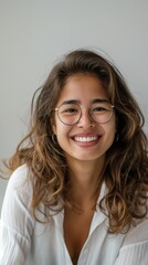 Wall Mural - A woman with brown hair and glasses smiles while looking at the camera