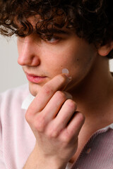 using acne pimple patch to clean the face from zits. young man uses acne stickers as bandage not to 
