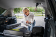 © Miljan Živković - mature blonde woman travel take stuff belongings from the back of car