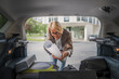 © Miljan Živković - mature blonde woman travel take stuff belongings from the back of car