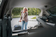 © Miljan Živković - mature blonde woman travel take stuff belongings from the back of car