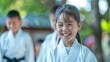 © Felix - A young girl in a white martial arts uniform smiles broadly during her training session, her face shining with joy and determination in an outdoor practice setting.