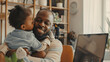 © Mahemud - Two children kissing their African-American father while he works from home, with copy space available.