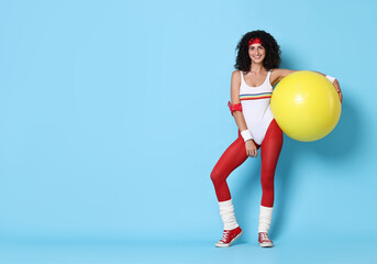 Wall Mural - Aerobics. Happy woman with fitness ball on light blue background, space for text