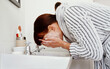 © ThaaJamSession/peopleimages.com - Woman, home and wash face in sink with soap for skincare and hygiene routine. Female person, bathroom and basin for natural process with skin product for facial treatment, self care and organic glow