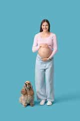 Canvas Print - Beautiful young pregnant woman with cute Cocker Spaniel dog on blue background