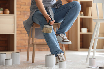 Poster - Young man with brush painting furniture at home, closeup