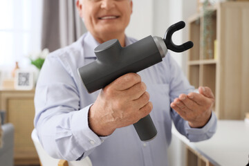 Canvas Print - Mature businessman with percussive massager in office, closeup