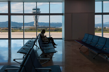 Wall Mural - Silhouette of young woman working on laptop and waiting for flight in the Airport - El Prat-Barcelona airport. This airport was inaugurated in 1963 - Barcelona, Spain 