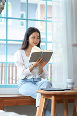 Young asian businesswoman enjoying to reading literature the book and relaxation with drinking coffee after analysis strategy about investment and planning of new startup project to working in cafe