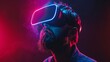 © Kateryna Kordubailo - A young bearded man wearing virtual reality glasses in a dark setting, representing augmented reality and future technology concepts, illuminated by neon light.