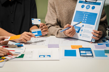 close-up of hands working on ux/ui design at a desk. papers with wireframes, prototypes, and mockups
