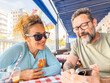 © simona - Adult couple checking and writing restaurant review feedback on social media pages after had lunch together. Happy clients writing comment about food to rate pizzeria. Tourist searching destinations