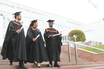 Wall Mural - Group of multiracial graduate students with diplomas on university background