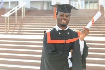 Wall Mural - I have finally graduated. Happy young African man in graduation gowns holding diploma