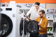 © Serhii - Couple choosing wasing machine at electronics store