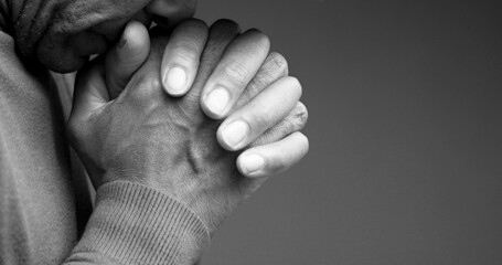 Wall Mural - man praying to god with hands together Caribbean man praying with black background with people stock photo