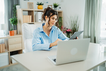 Wall Mural - One young beautiful caucasian business woman working in office on laptop and looking through charts