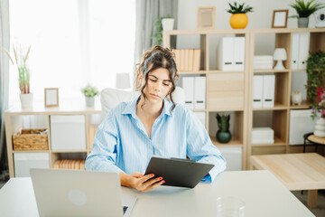 Wall Mural - One young beautiful caucasian business woman working in office on laptop and looking through charts