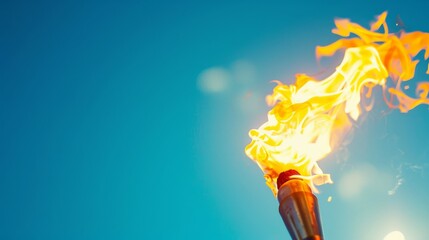 Torch with flame against clear blue sky, close-up. Inspirational and motivational concept