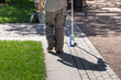 © Sergei - A man with a cane walks on a sidewalk