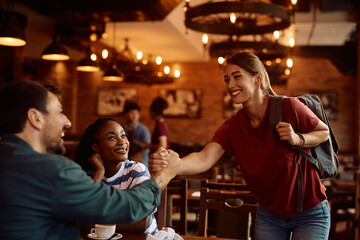 Happy friends greeting while gathering in  pub.