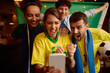 © Drazen - Excited soccer fans cheering while watching match on smart phone.