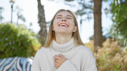 Poster - A smiling blonde woman with blue eyes, enjoying the outdoors in a sunlit park.