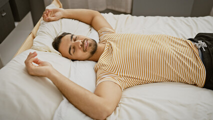 Poster - A relaxed young man with a beard napping peacefully in a modern bedroom setting.