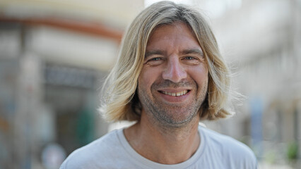 Sticker - Handsome man with long blond hair smiling on a sunny urban street