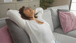 © Krakenimages.com - A middle-aged hispanic woman relaxing on a sofa in her living room with a serene expression, showcasing domestic tranquility and comfort.