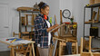 © Krakenimages.com - African american woman with curly hair taking notes in a carpentry workshop.