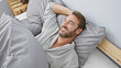 © Krakenimages.com - Smiling middle-aged man with a beard lying comfortably in bedroom wearing pajamas