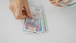 © Krakenimages.com - Adult female counts polish zloty banknotes in an indoor office setting, denoting finance.