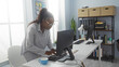 © Krakenimages.com - Woman working in modern office setting, utilizing desktop computer with organized bookshelves, bright daylight setting, concentration visible